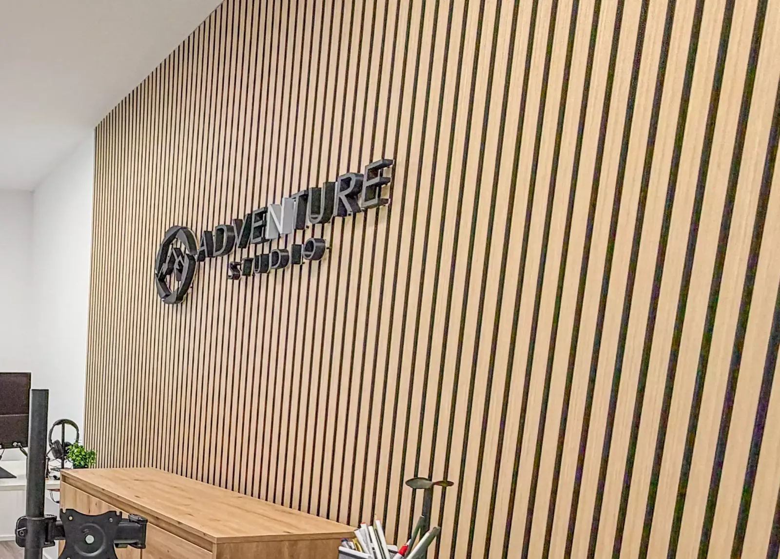 Holzlamellenwand mit Adventure-Logo